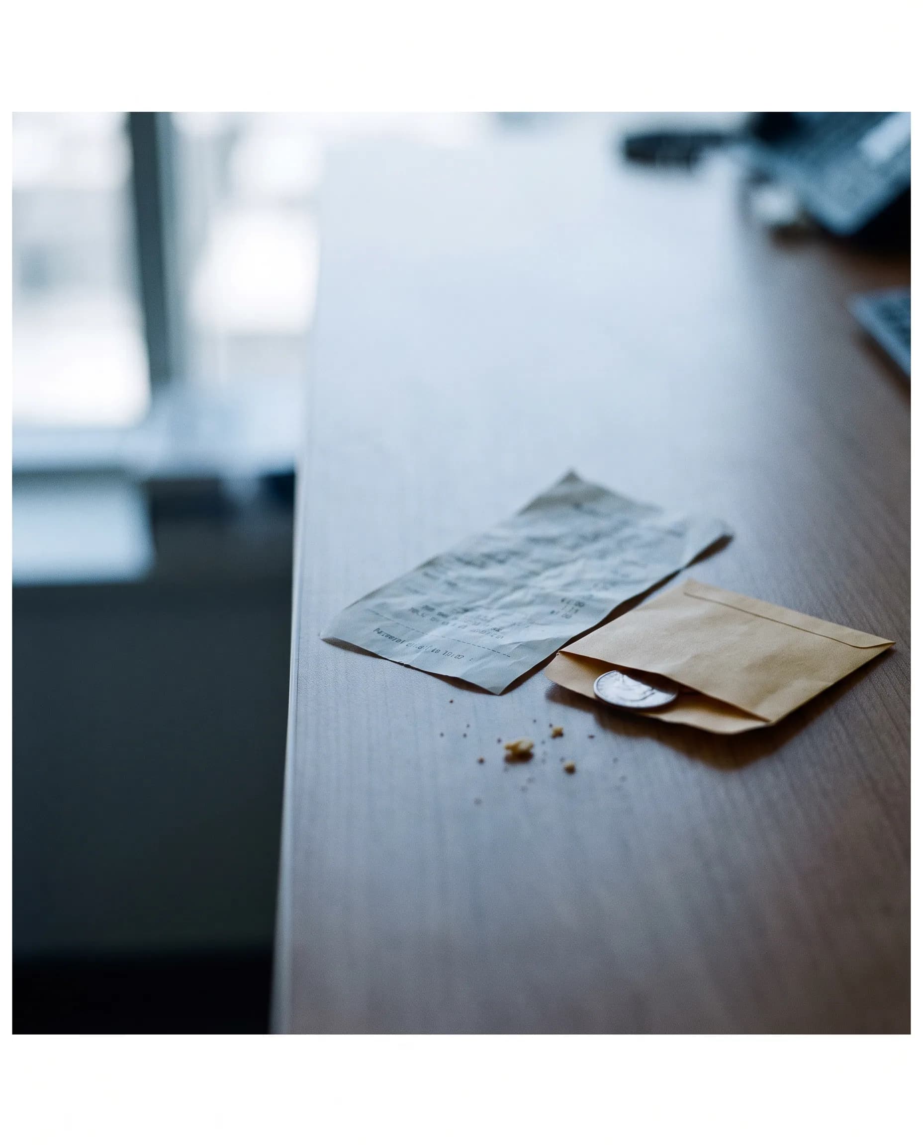 A receipt, an envelope and a coin on a desk: a small, clearly shown commission.
